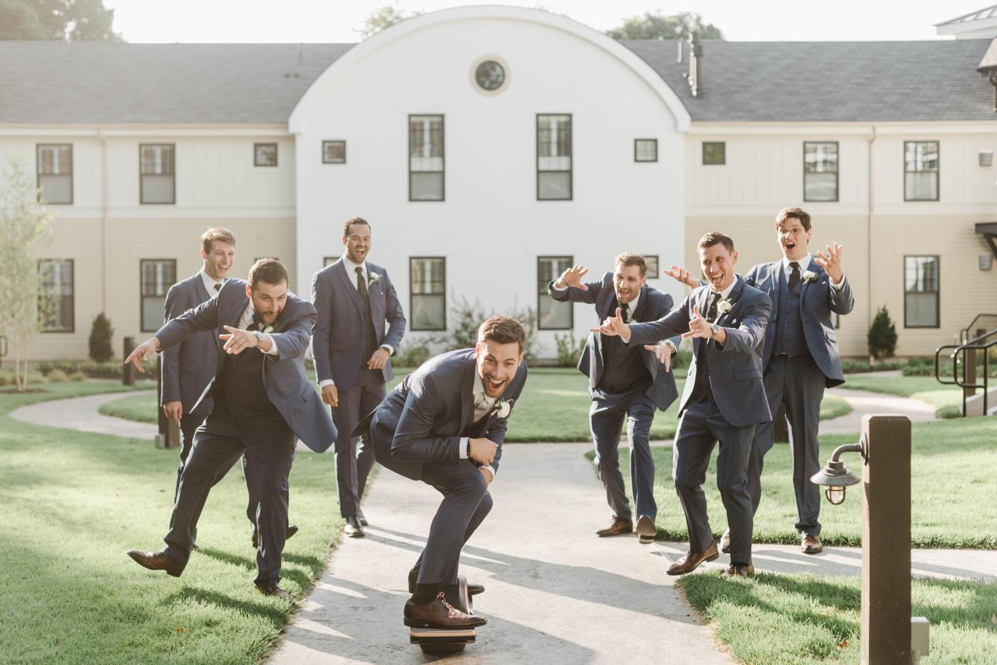 groomsman in courtyard with groom on skateboard