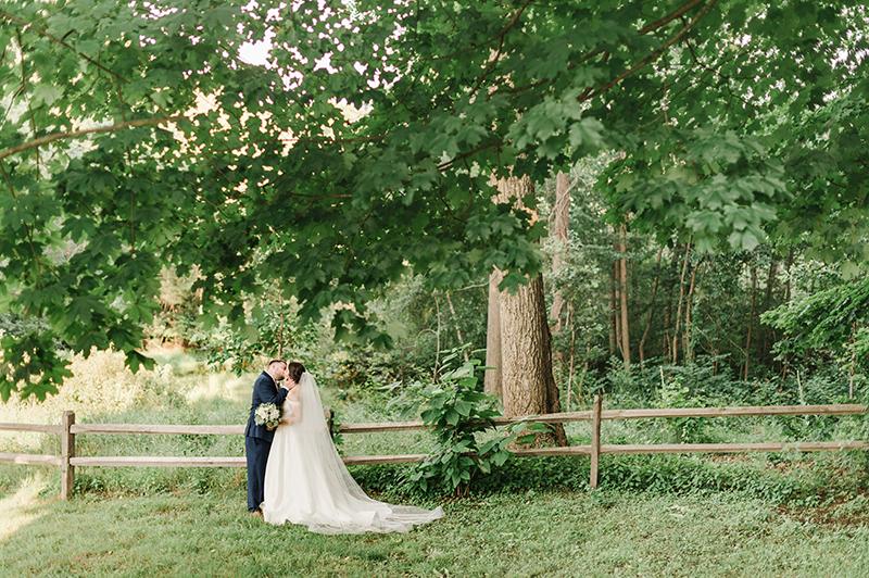 Bride and groom kiss in woods