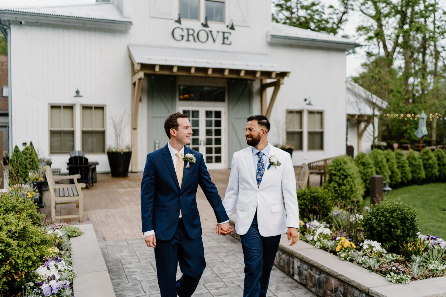 grooms outside grove entrance in wedding suits 