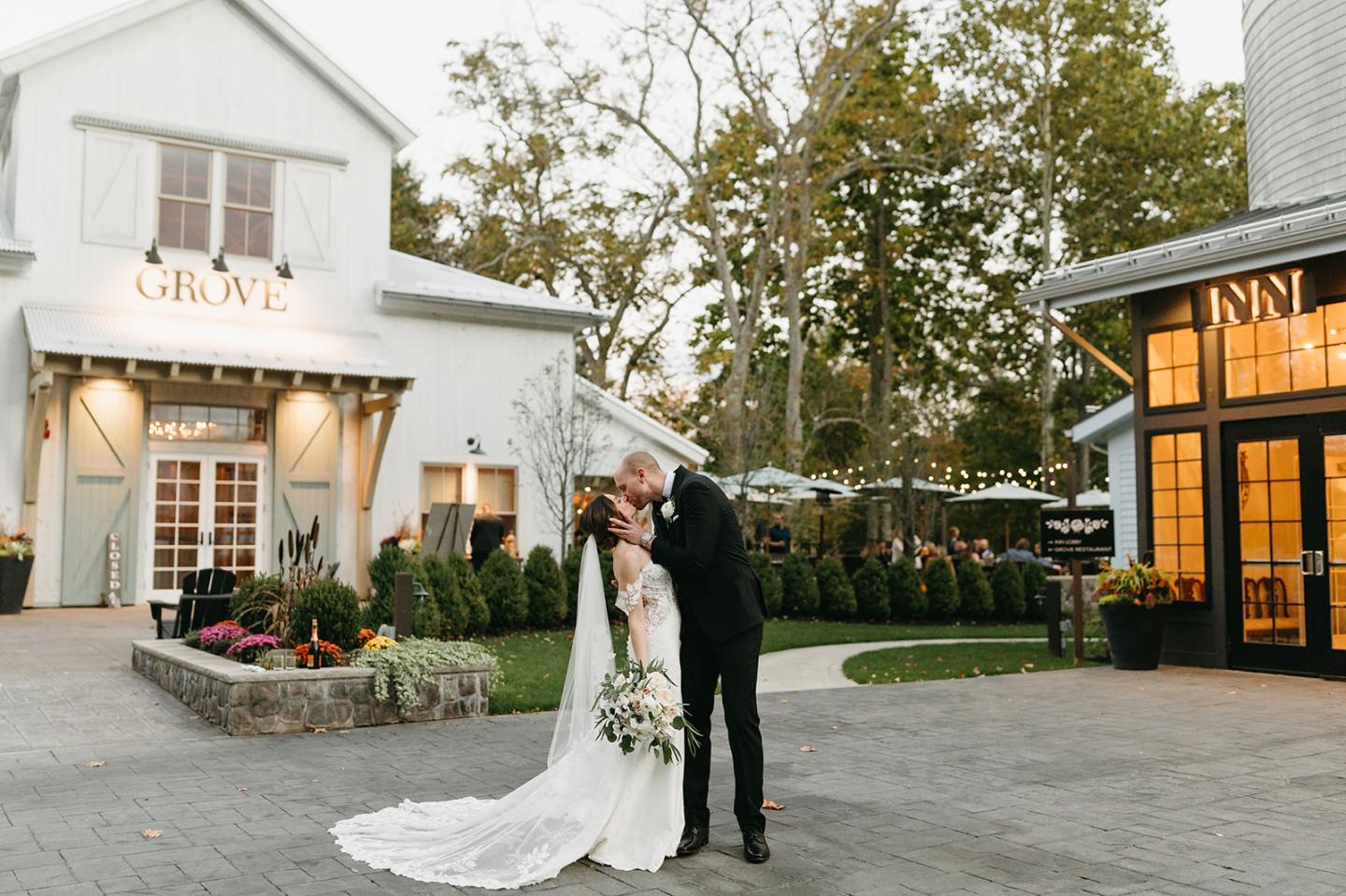 bride and groom kiss in front of grove entrances