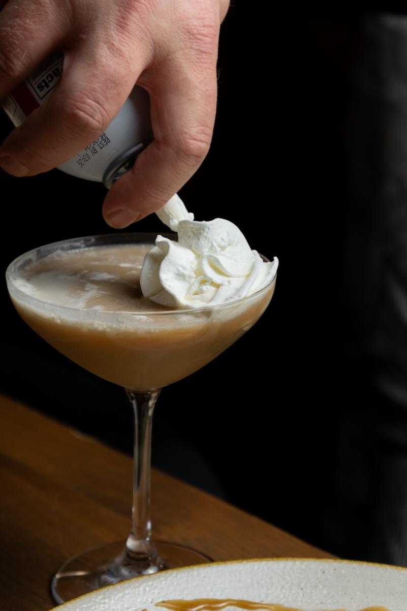 white chocolate espresso martini with whipped cream being added