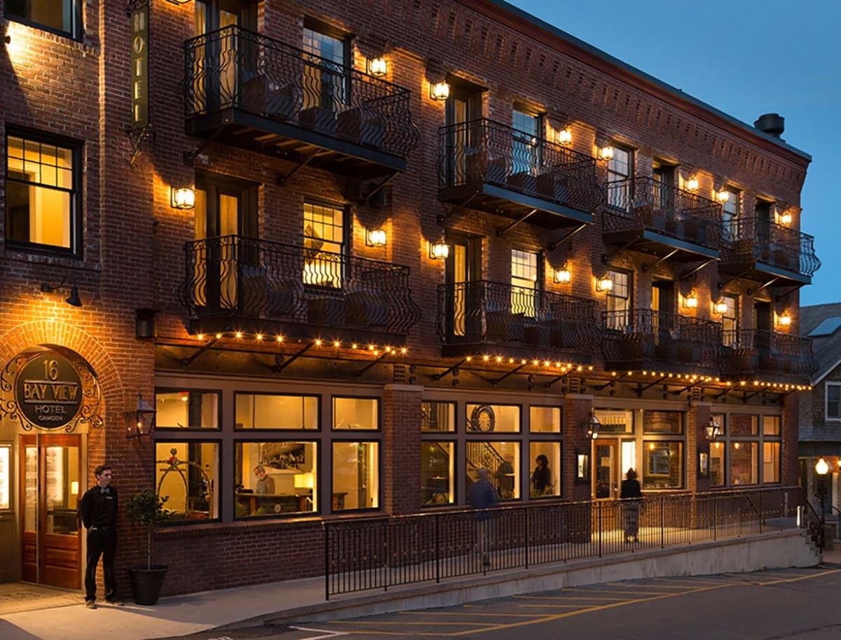 Brick building at dusk with warm lights and balcony railings.