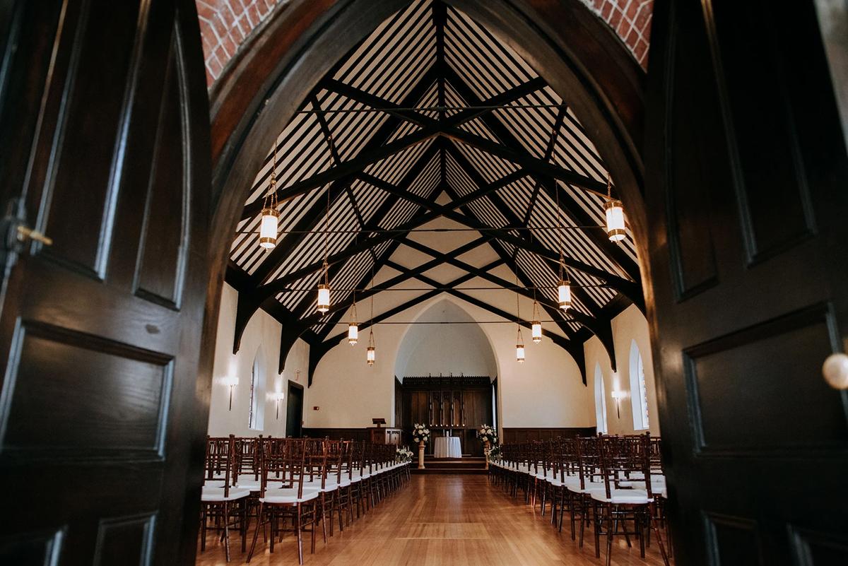 Church interior with high wooden beams and rows of chairs.
