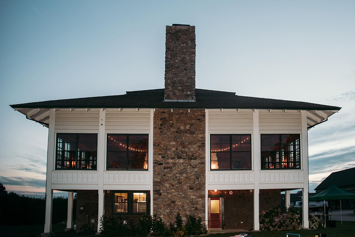 Two-story house with stone chimney at sunset.