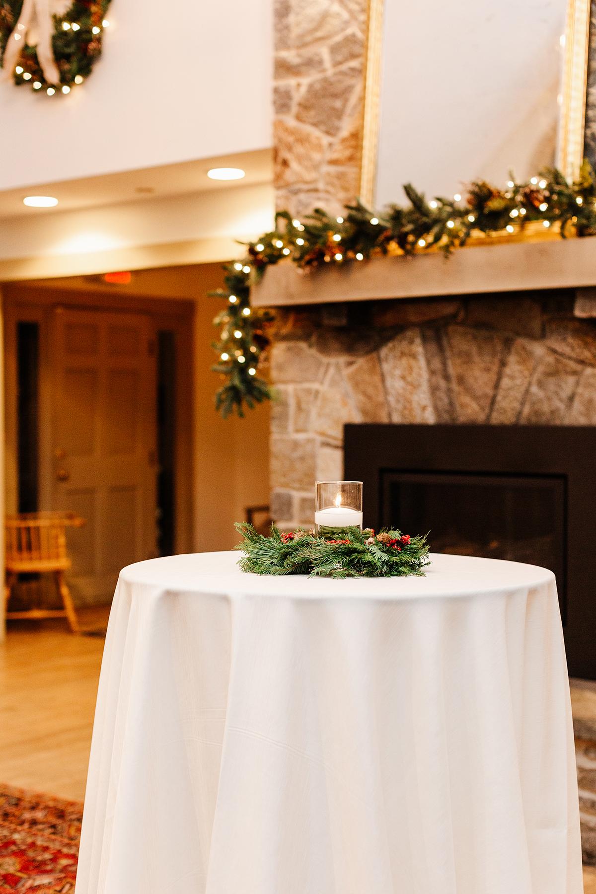 Elegant room with festive garland, stone fireplace, and table with greenery centerpiece.