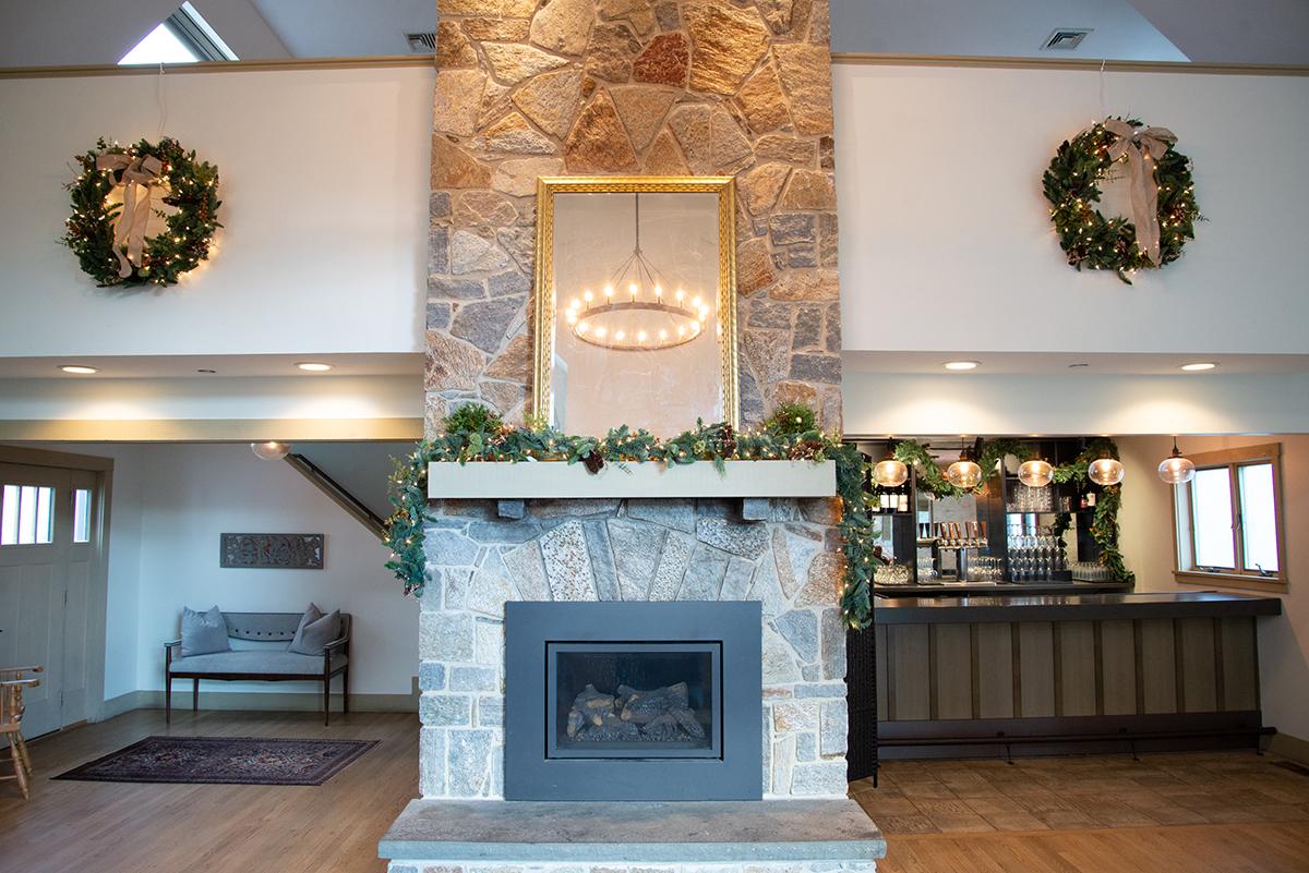 Stone fireplace with wreaths and greenery, warm cozy interior.