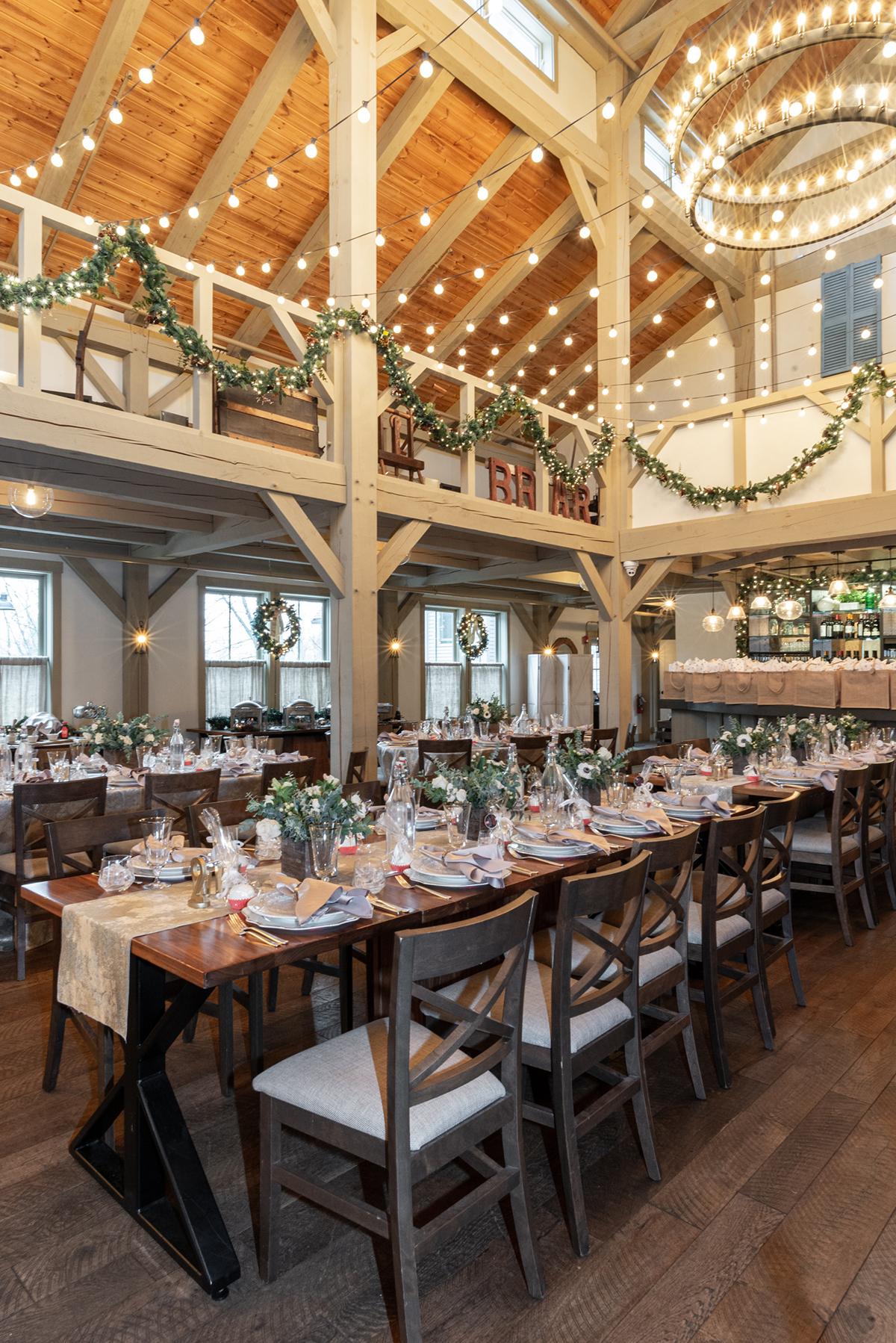 Elegant dining room with decorated long tables and string lights overhead.