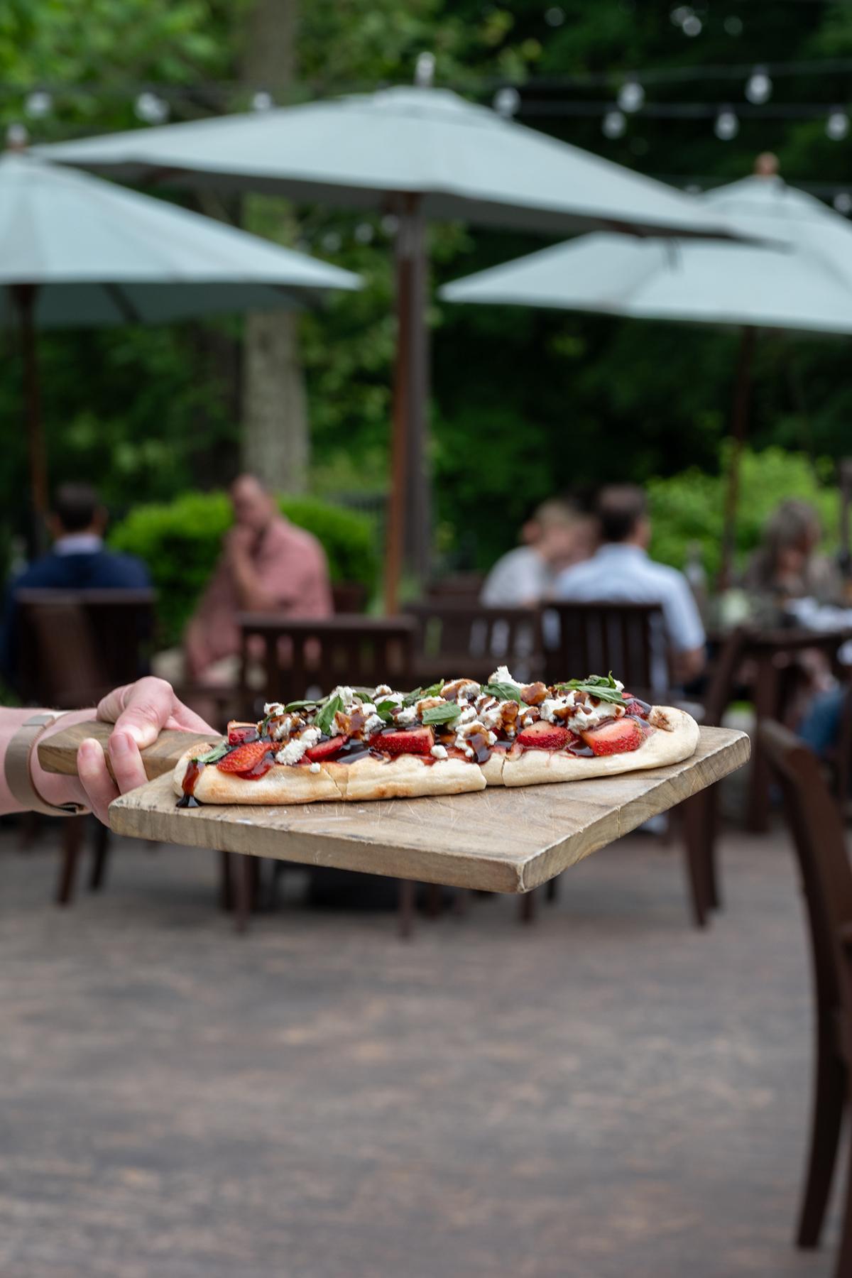 Flatbread pizza served outdoors under umbrellas.