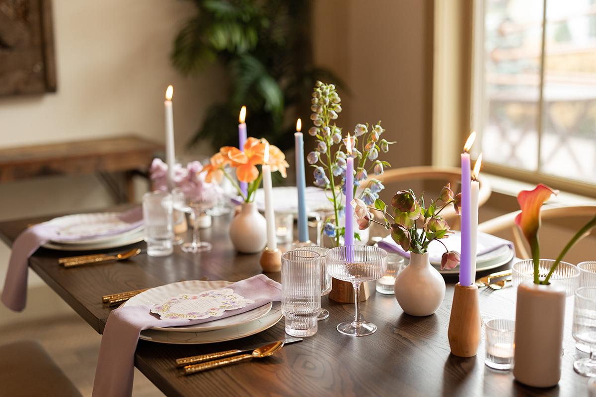 Elegant table setting with floral centerpieces and lit candles in a cozy room.