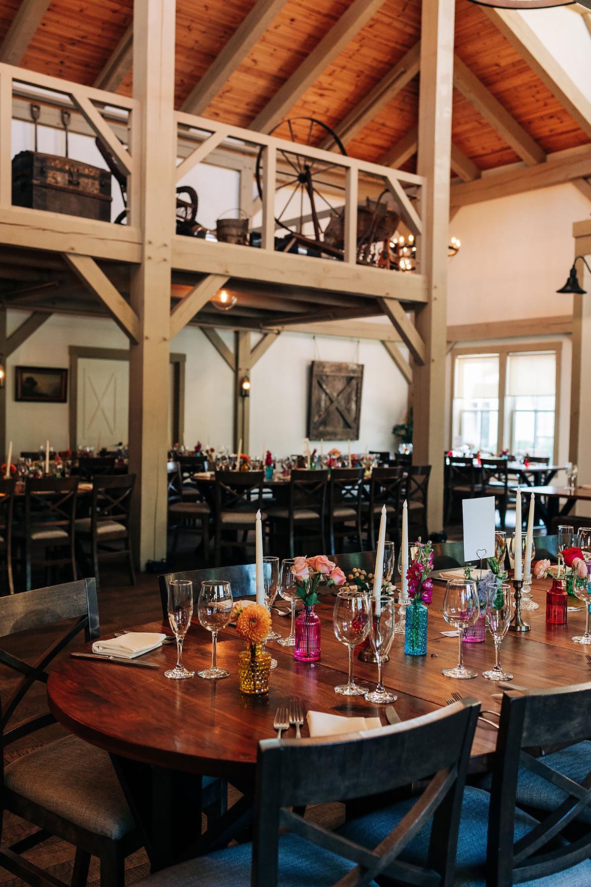 Rustic dining room with wooden tables, floral centerpieces, and vaulted ceiling.