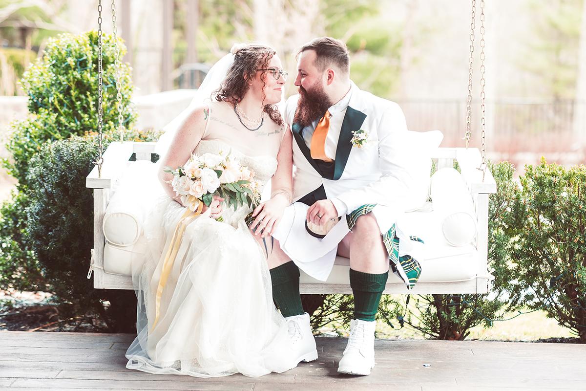 Bride and groom sitting on a white couch, sharing an intimate moment.