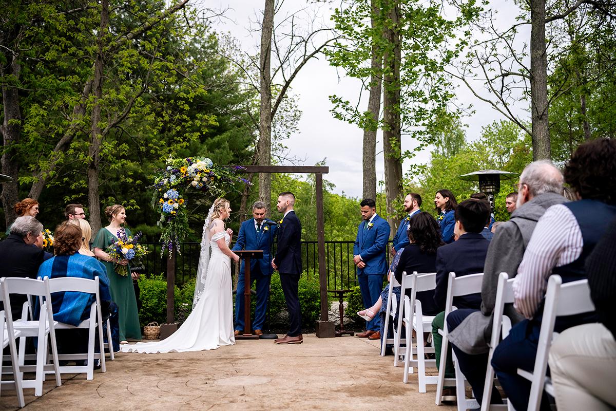Outdoor wedding ceremony in a forest, bride and groom exchanging vows.