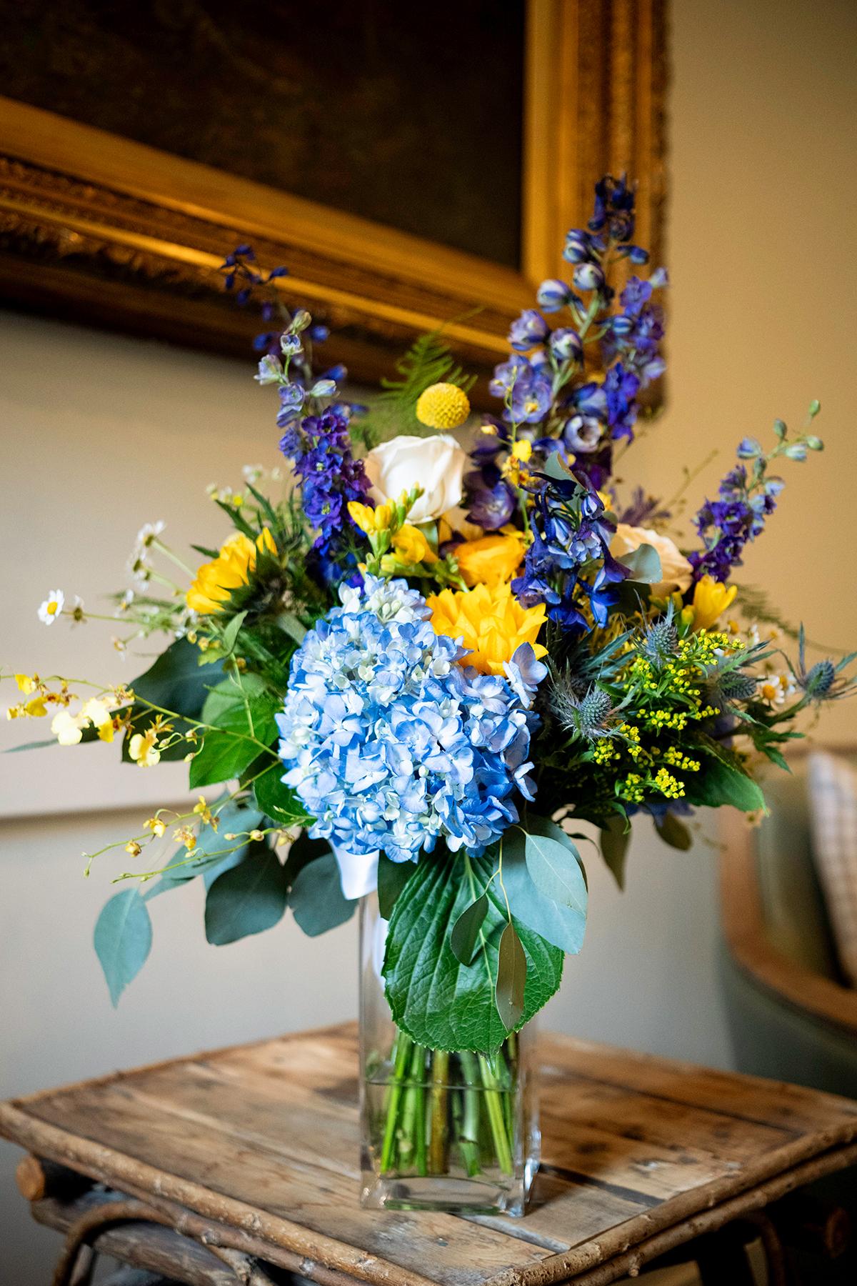 Vibrant flower bouquet with blue and yellow blooms in a glass vase.