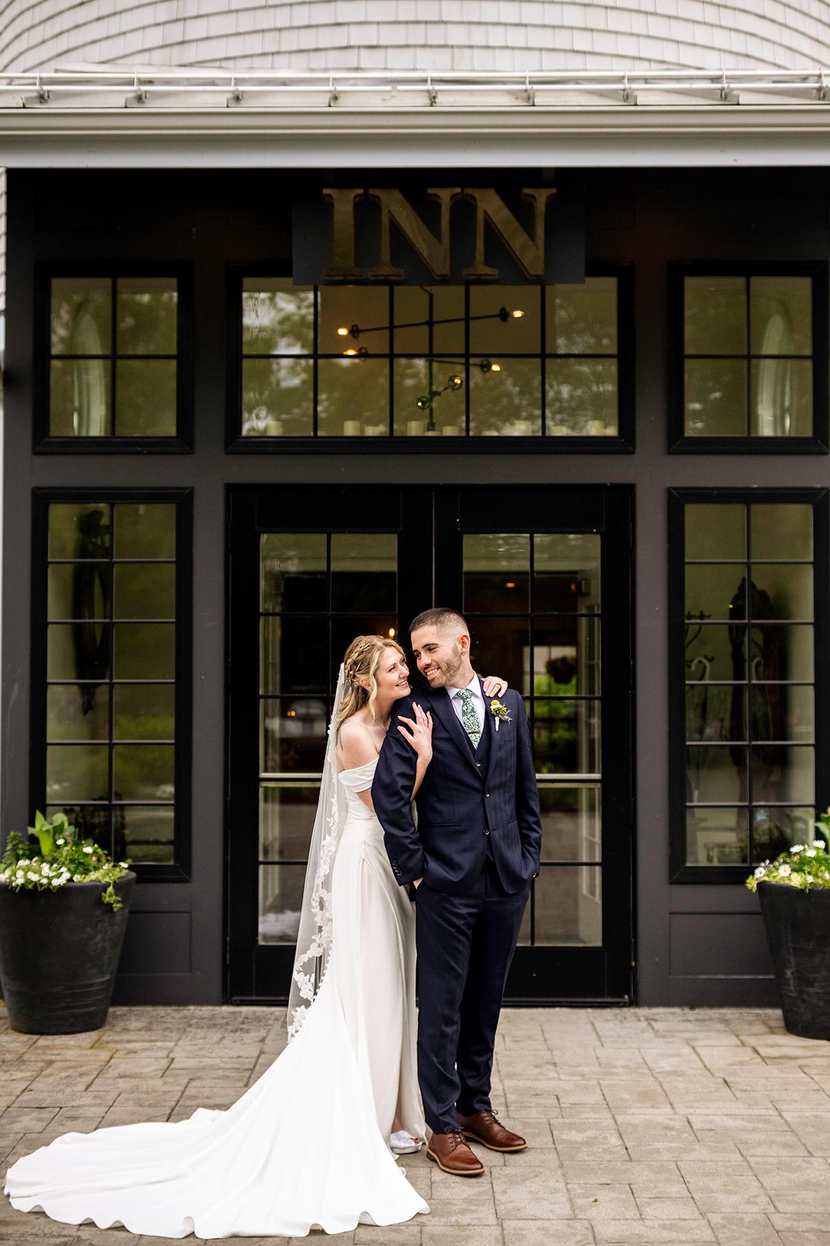 Bride and groom stand lovingly outside an inn.