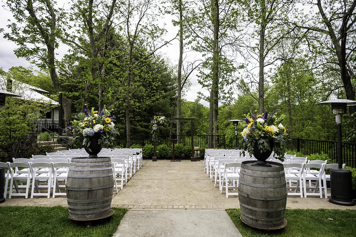 Outdoor wedding setup with chairs, flowers, and trees.