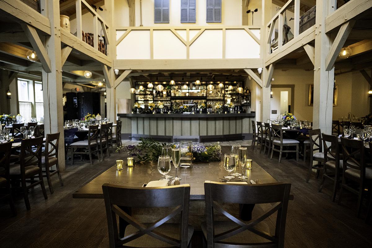 Spacious dining room with wooden beams and elegant table settings.
