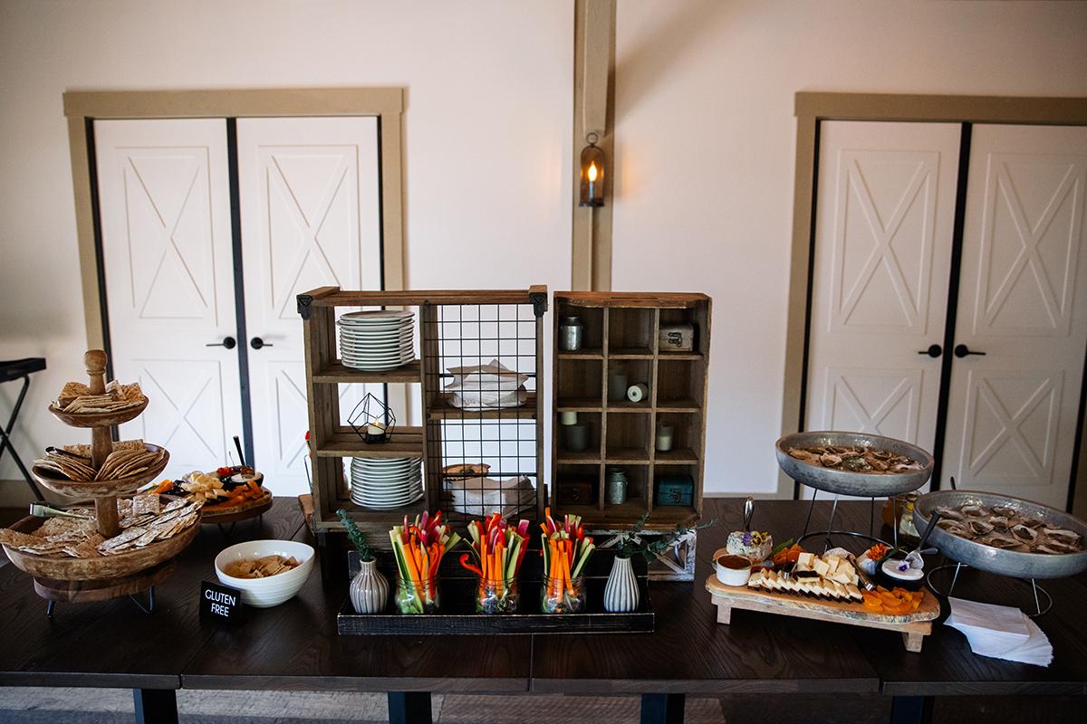 Buffet table with snacks, dishes, and decorative shelves in a warmly lit room.