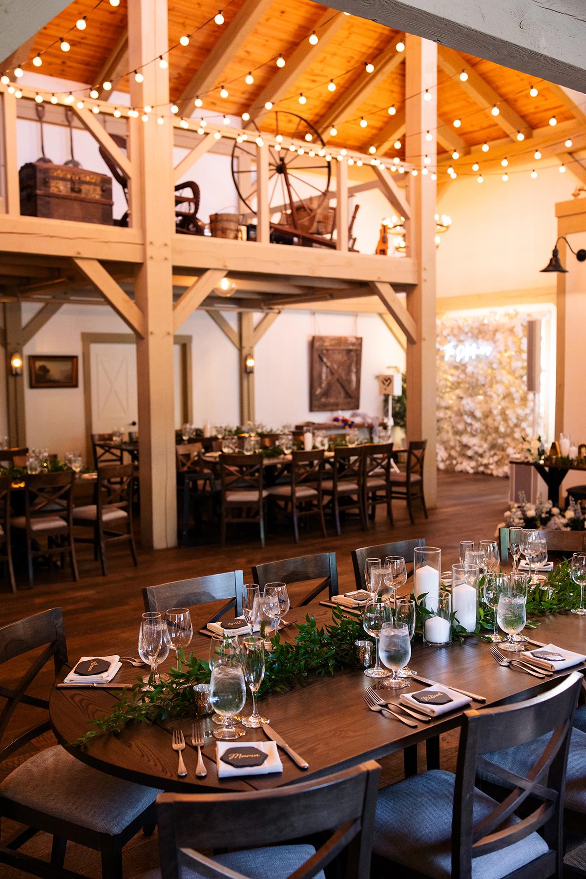 Rustic banquet hall with wood decor, string lights, and set dining tables.