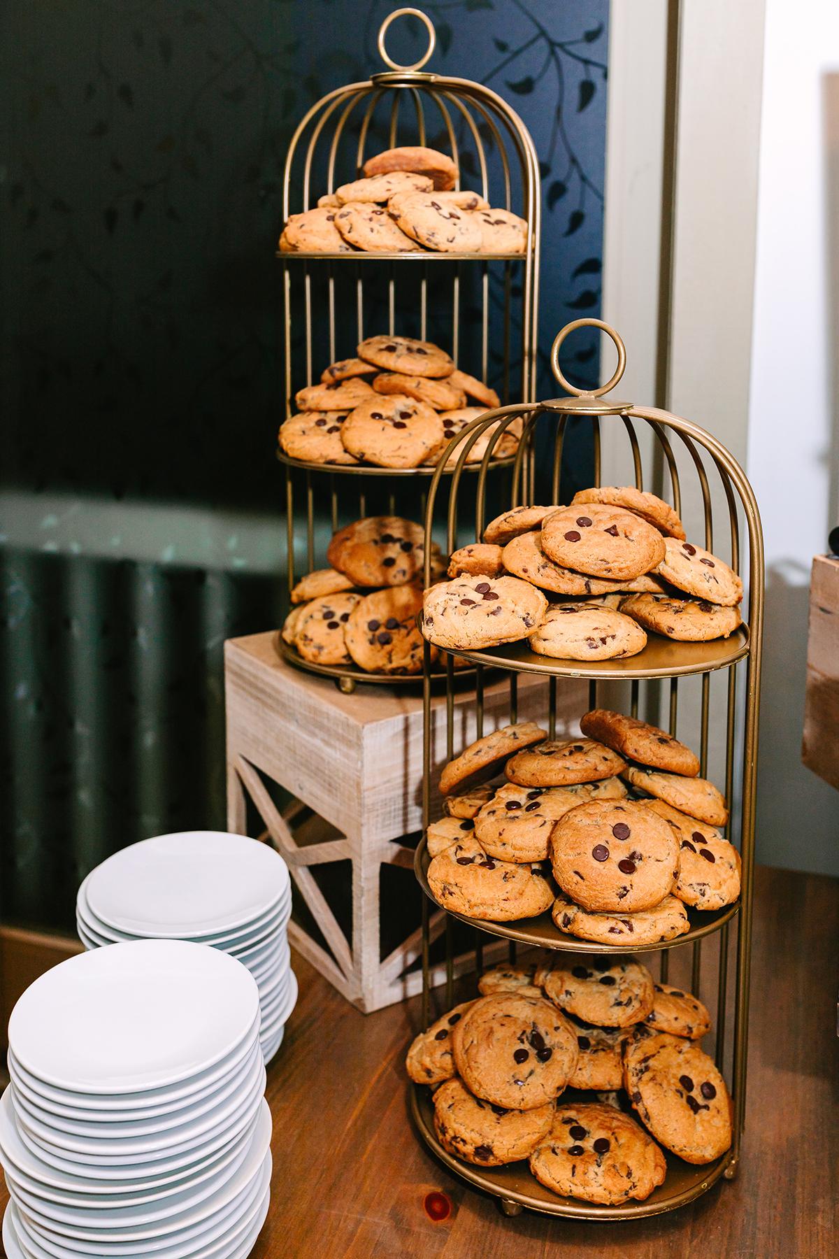 Cookies stacked on tiered trays next to a pile of plates.