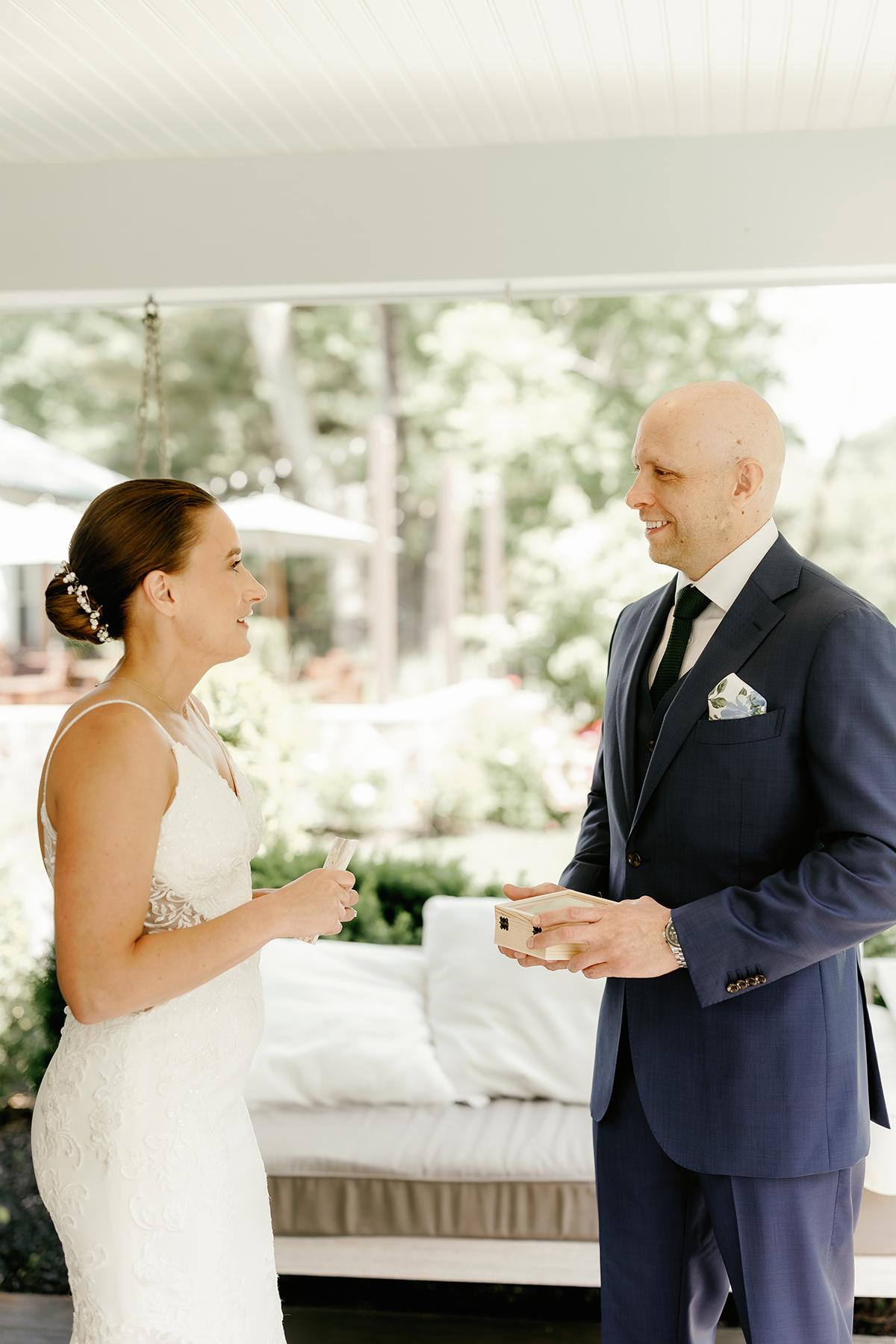 Bride and groom smiling, exchanging vows indoors.