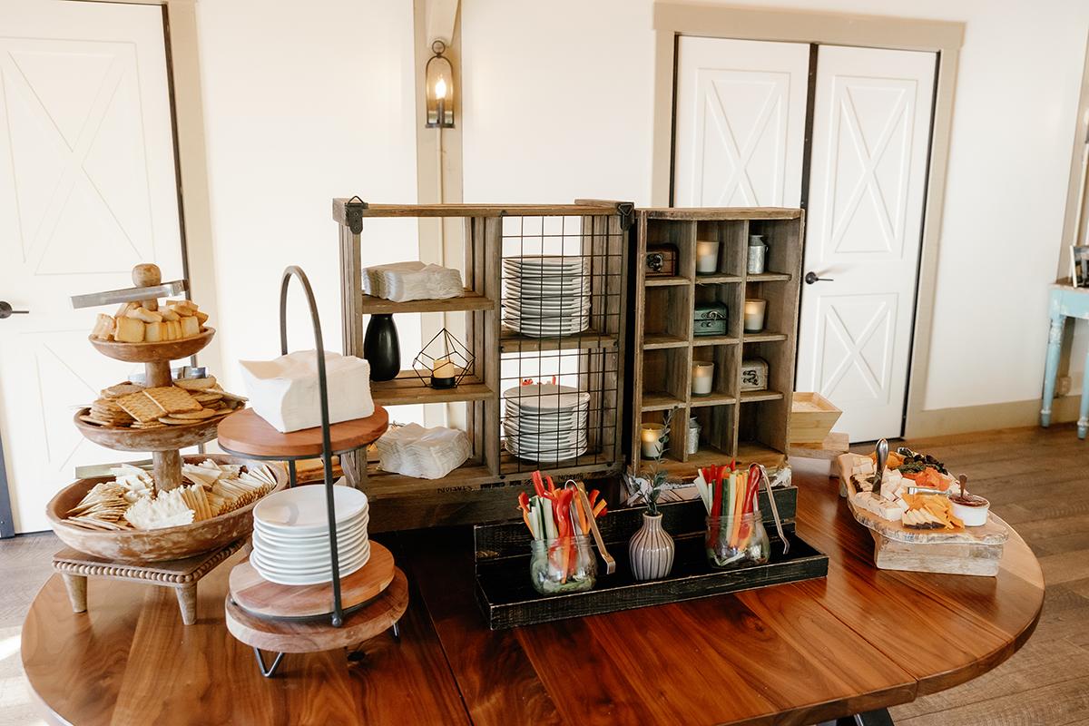 Buffet table with assorted plates, baskets, and snacks in a cozy room.