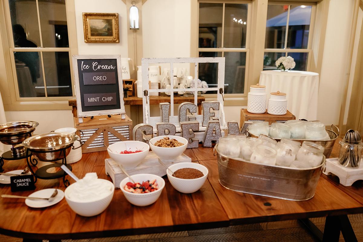 Ice cream sundae bar with toppings in bowls on a wooden table.