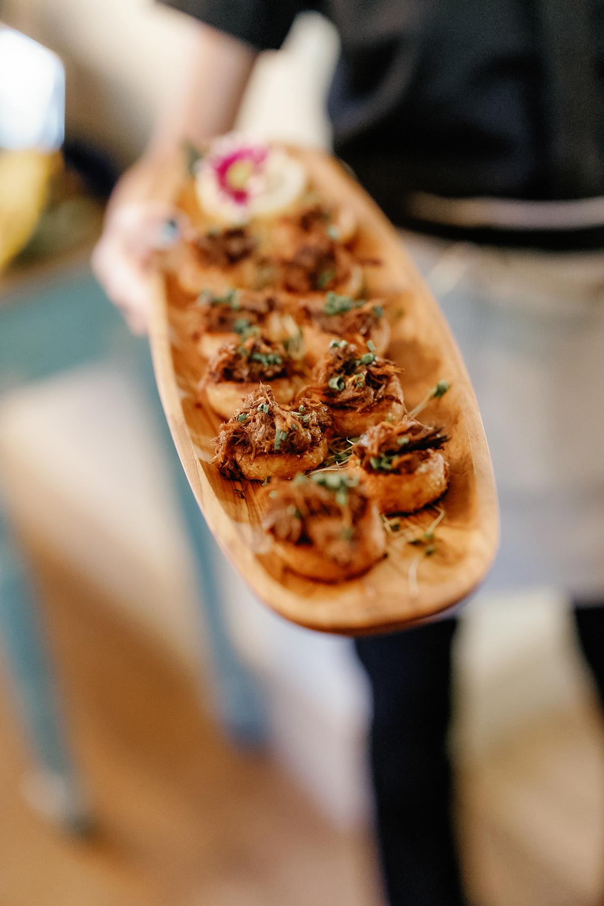 Appetizers on wooden platter, professionally presented.