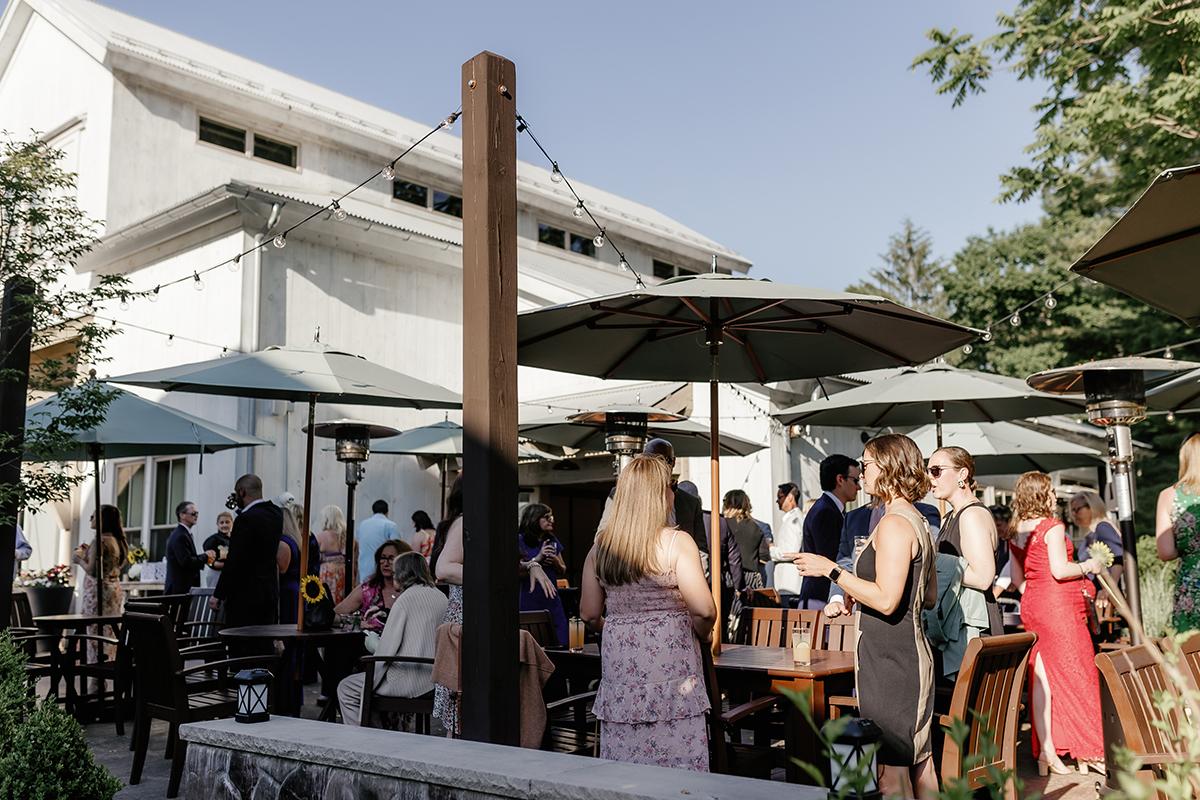 Outdoor gathering with people at tables under green umbrellas, sunny day.