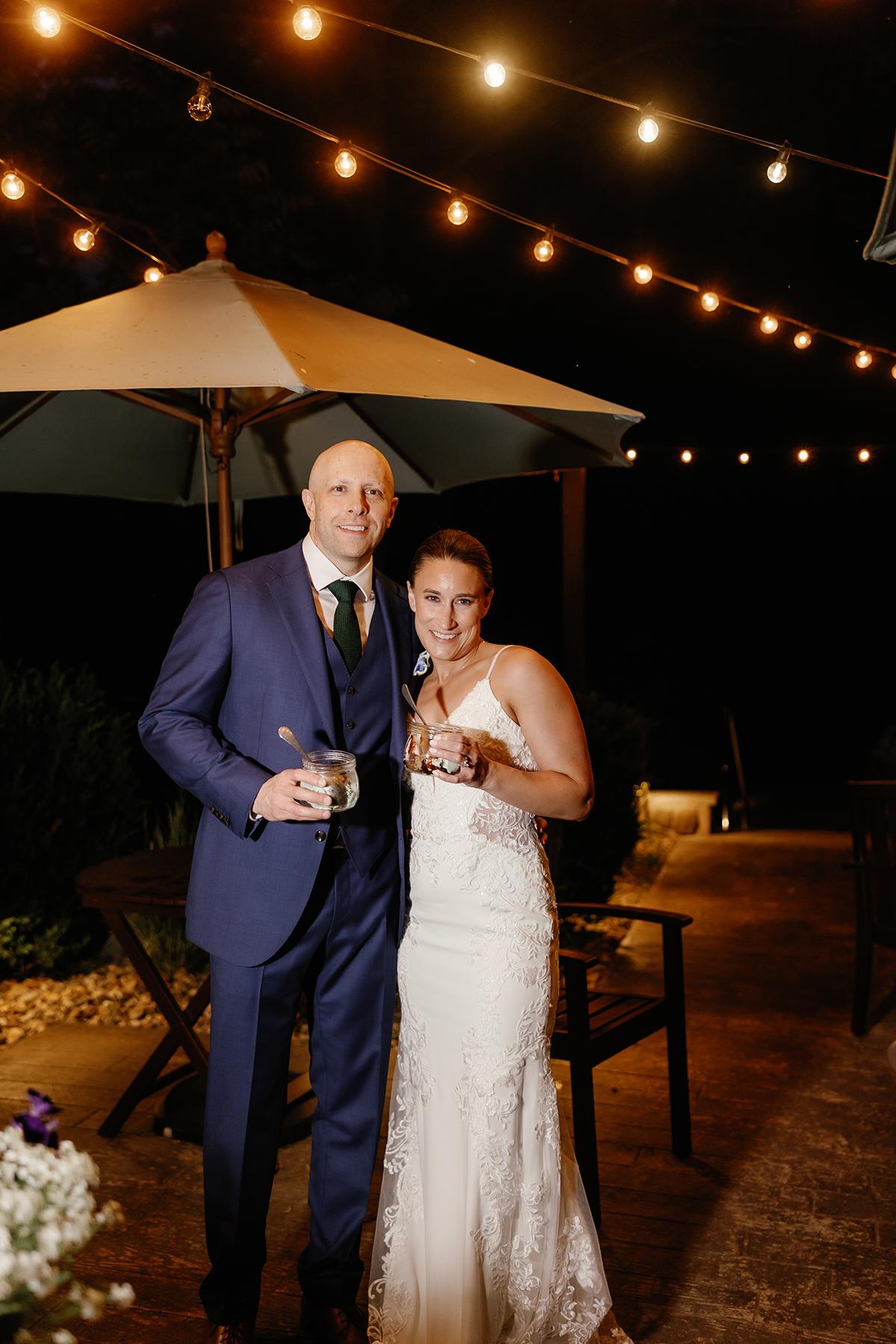 Wedding couple smiling under string lights at night.
