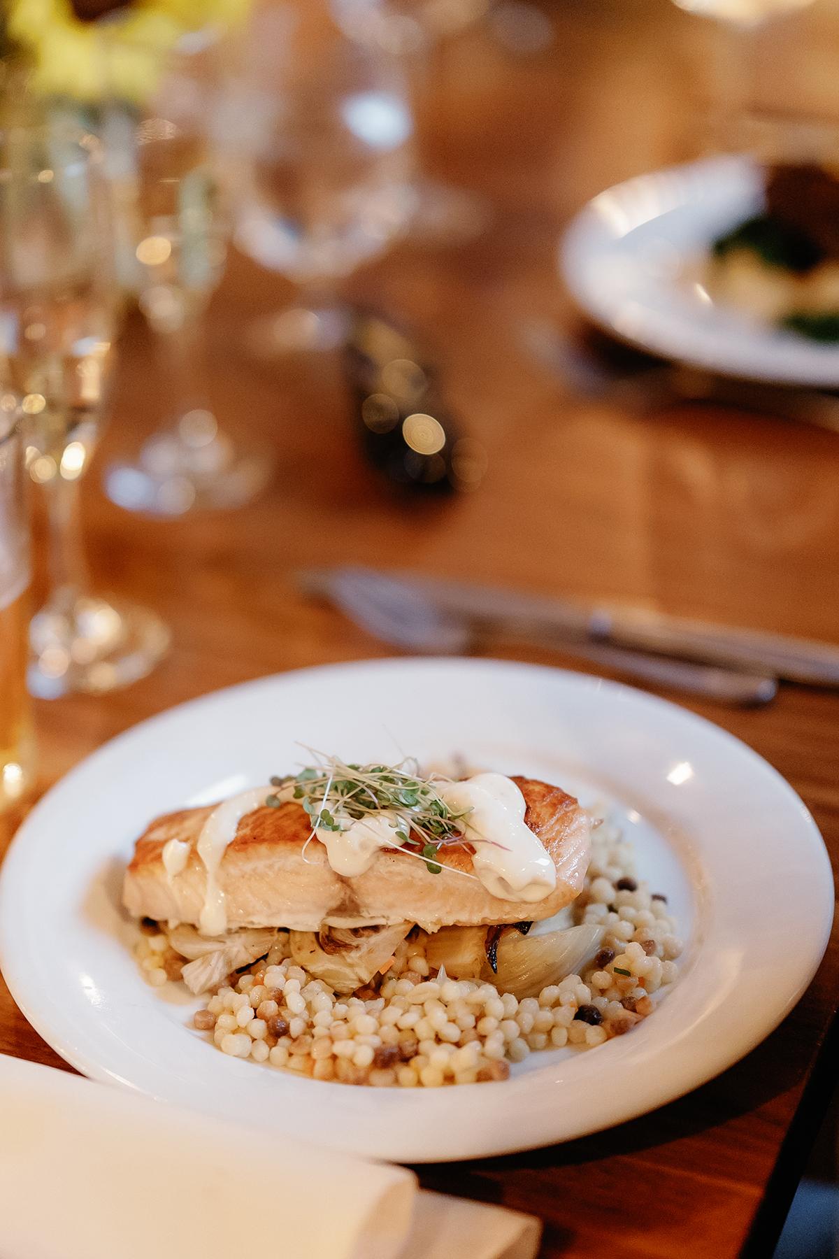 Grilled chicken on risotto with herbs, served on a wooden table.
