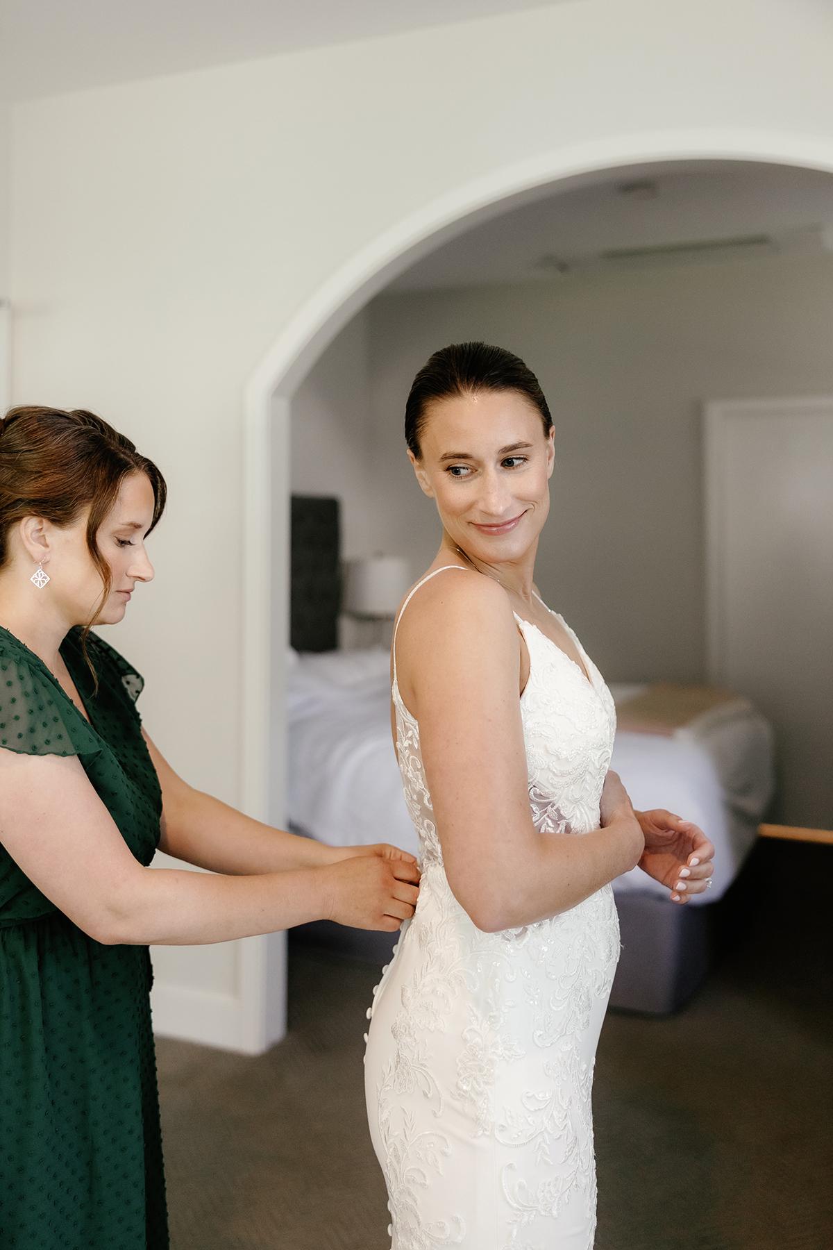 Woman in white dress being helped by another woman in a green dress.