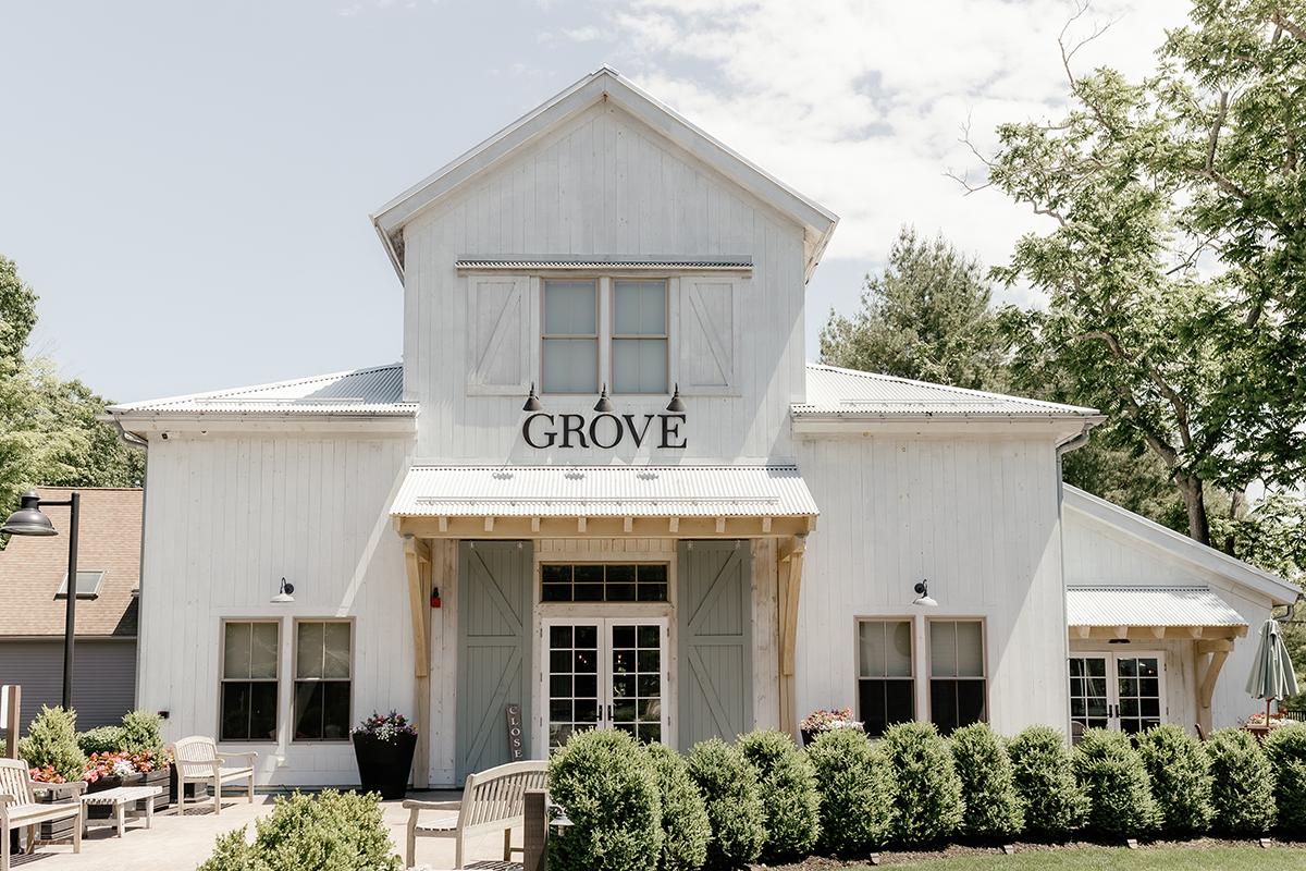 White building with "Grove" sign, surrounded by bushes and trees.
