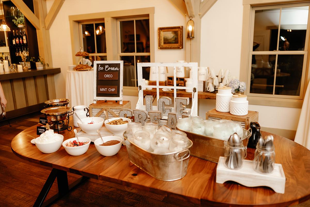 Coffee station with cups, ice bucket, and syrup containers on a wooden table.