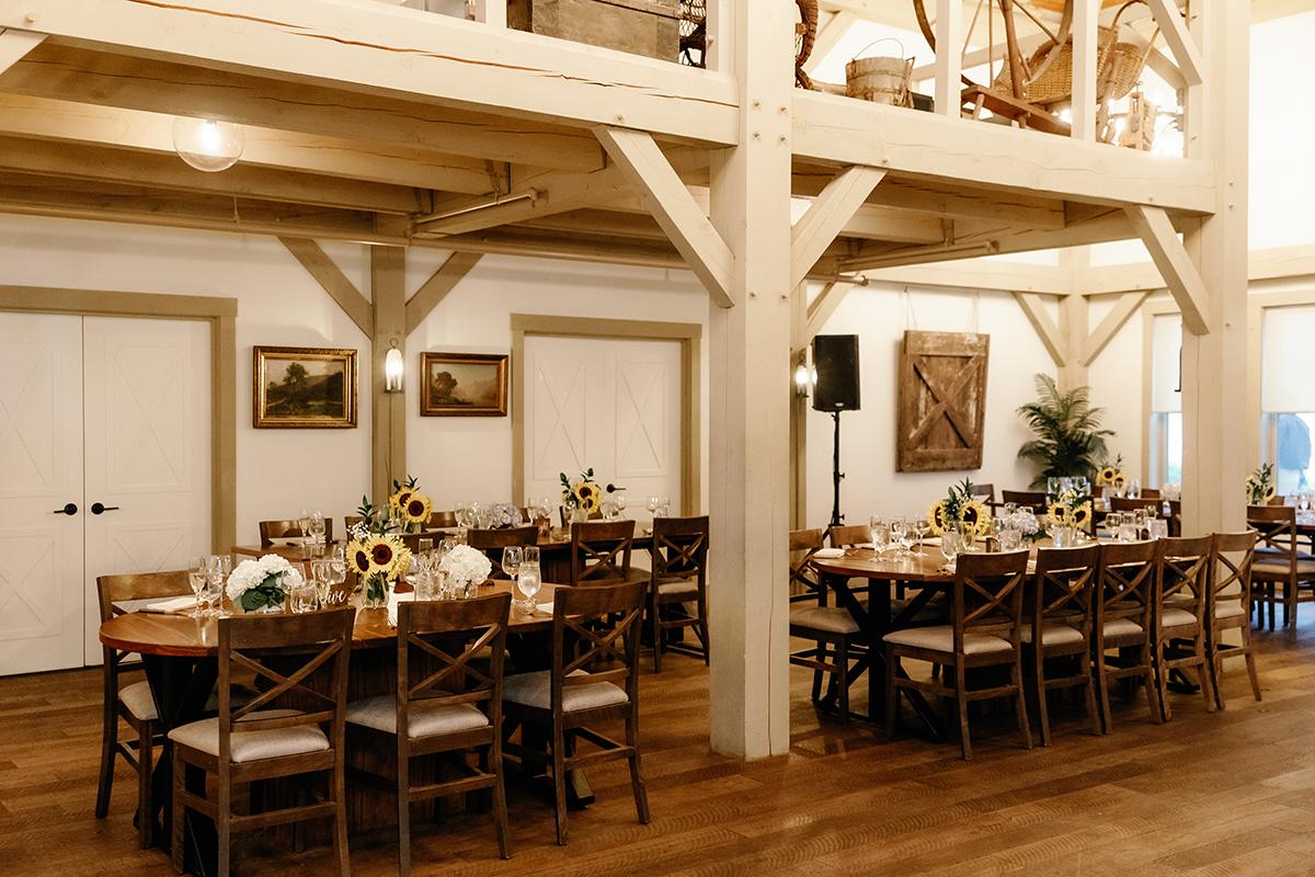 Rustic dining room with wooden tables, sunflowers, and framed paintings on the walls.