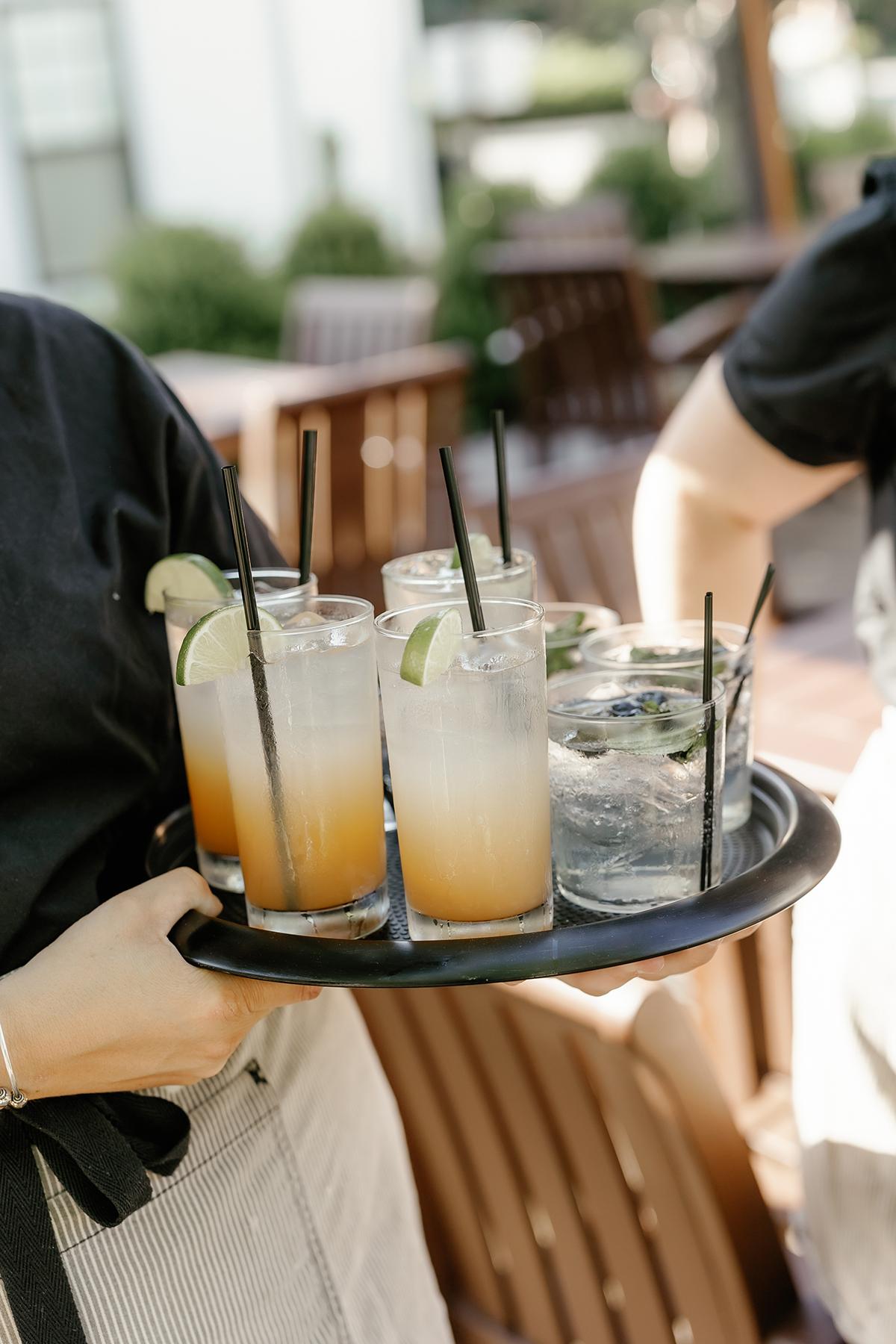 Tray with iced cocktails and lime slices outdoors.