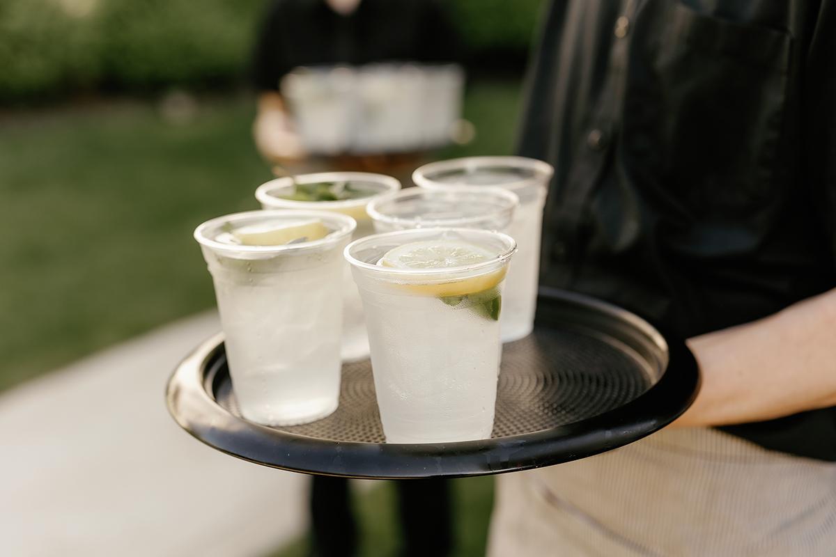 Drinks on a tray with lemon slices, outdoor setting.