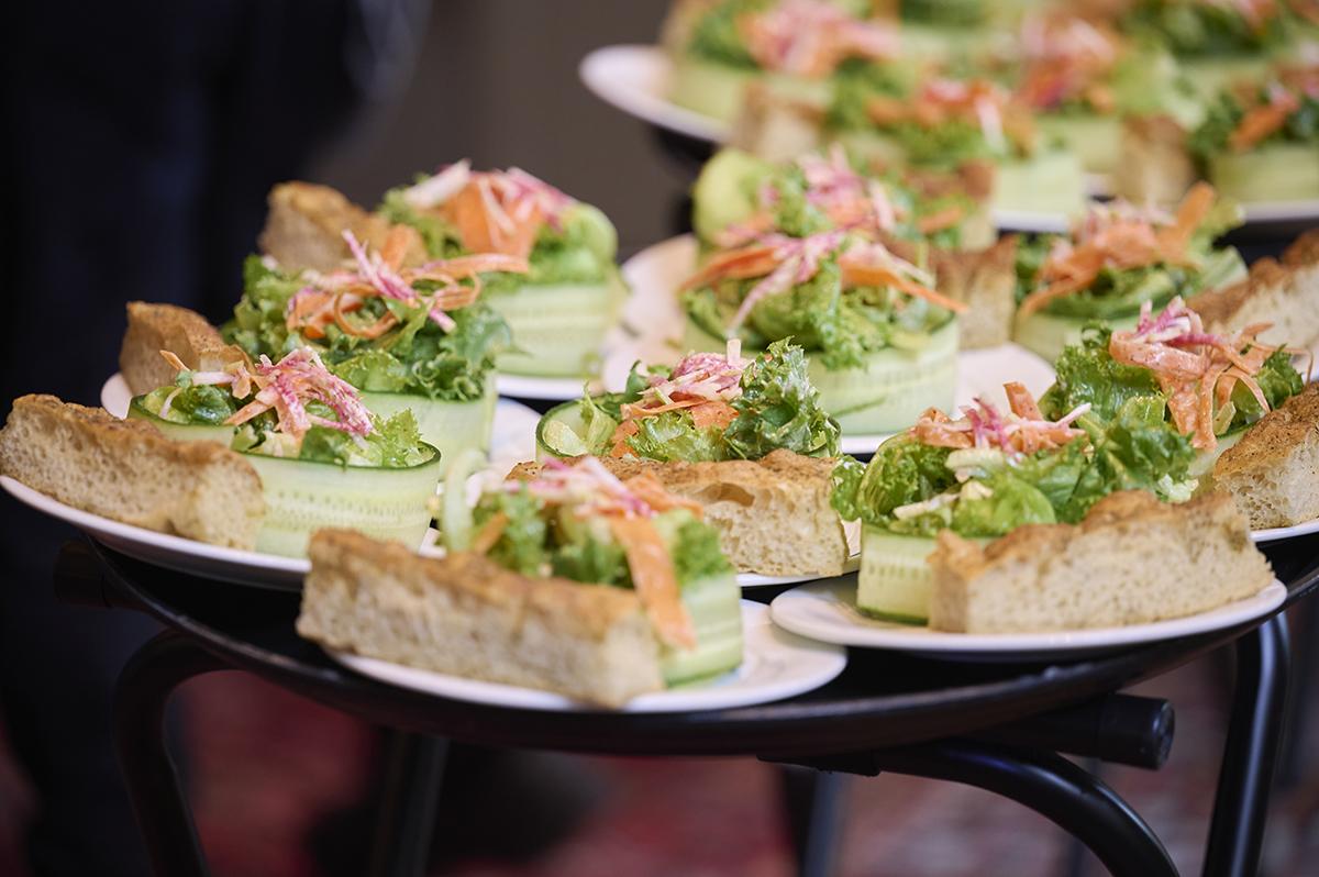Plates of sandwiches with lettuce and grated vegetables on a black tray.