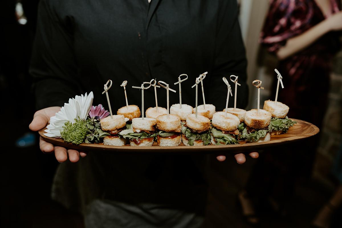 Tray with appetizers on skewers, garnished with greens and flowers.