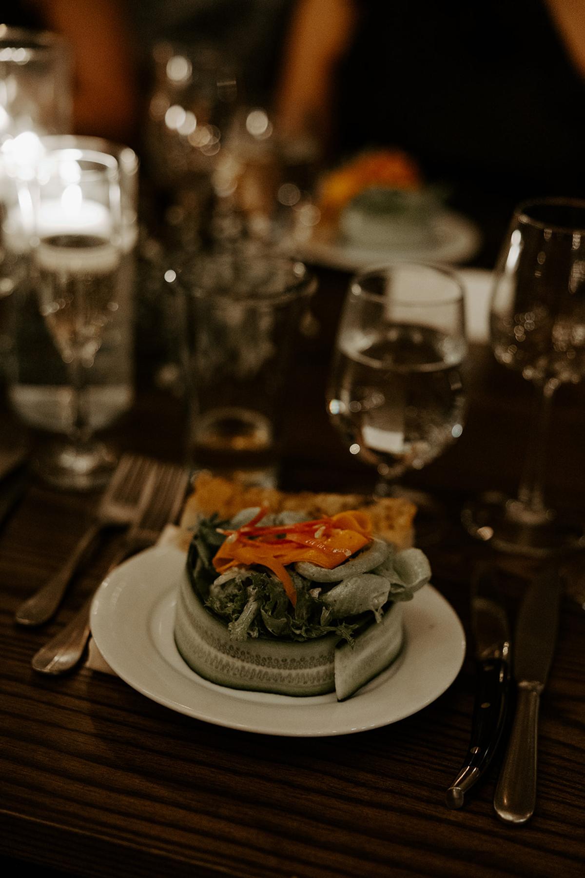 Salad with colorful toppings on a set dining table with candles.