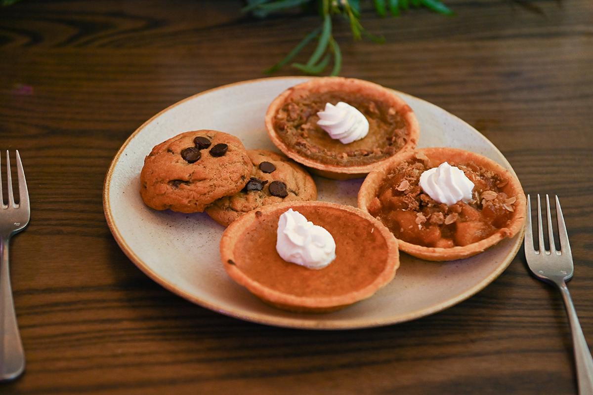 Tarts and cookies on a plate with forks, topped with whipped cream.