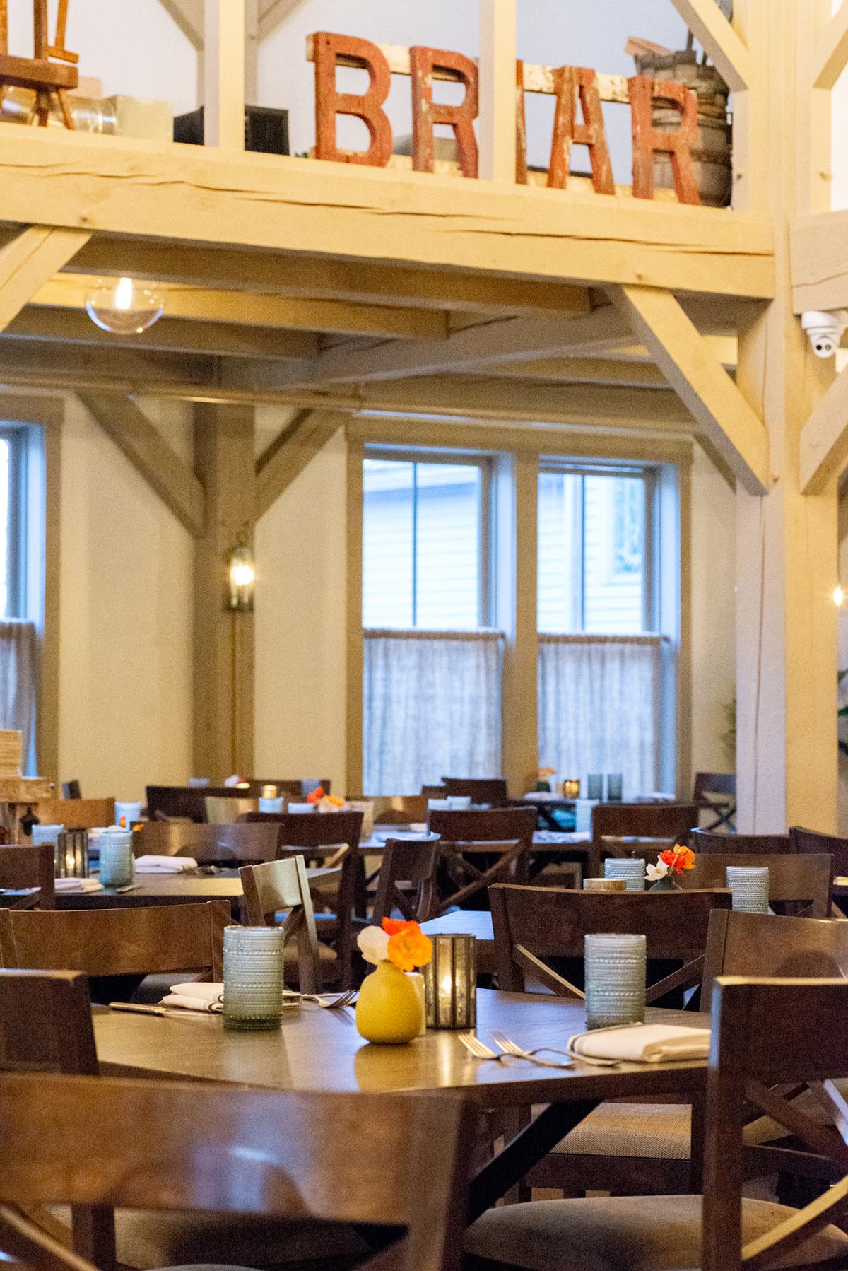 Dimly lit restaurant with wooden tables, colorful vases, and the word "BRIAR" above.