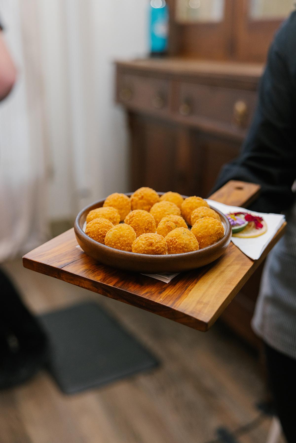 Plate of golden fried balls on a wooden tray.