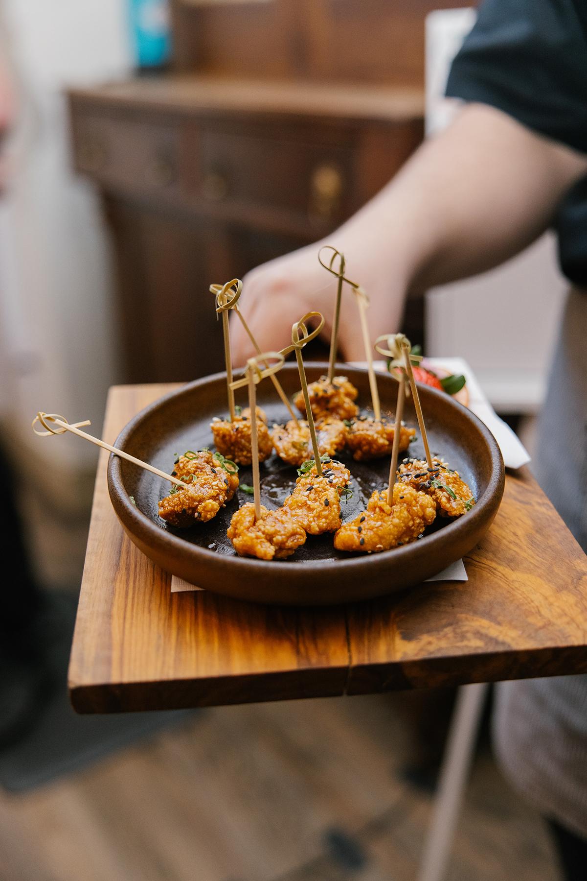 Skewered appetizers on a wooden tray being served.