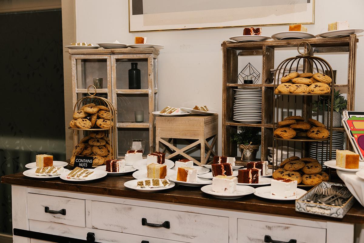 Dessert buffet with pastries and cakes displayed on a wooden table.