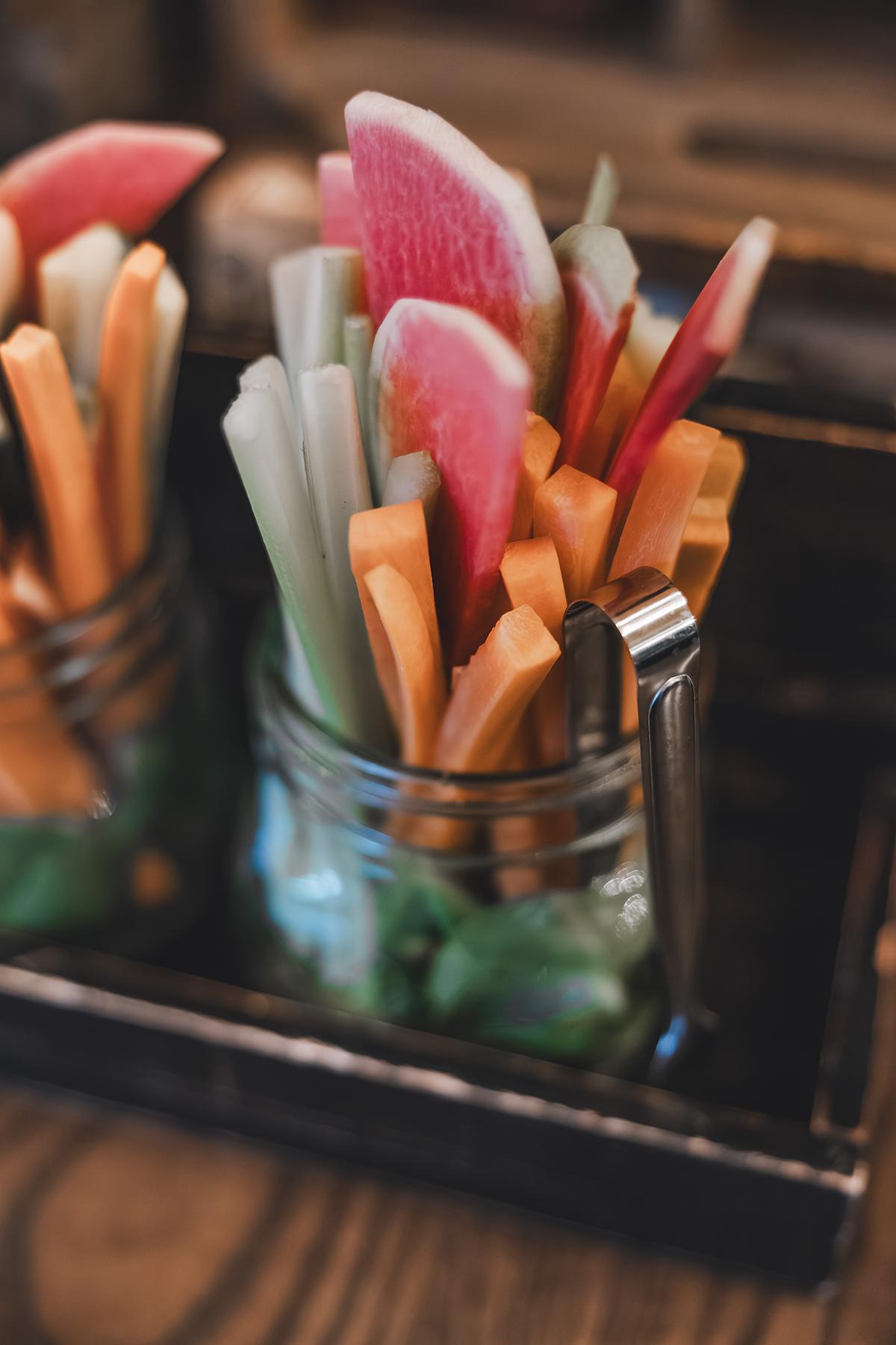 Colorful vegetable sticks in a glass jar, including carrots and radishes.