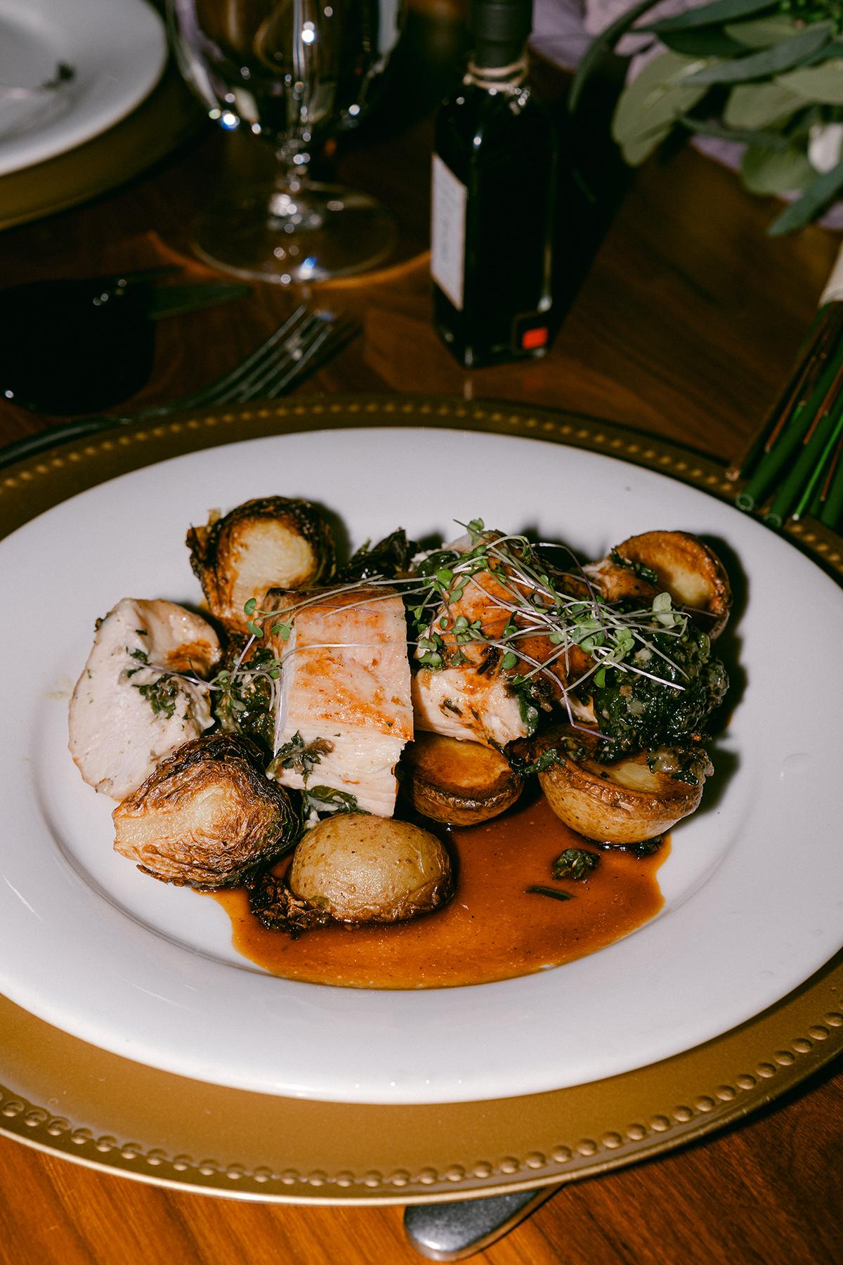 Roasted chicken with baby potatoes on a white plate, garnished with herbs.