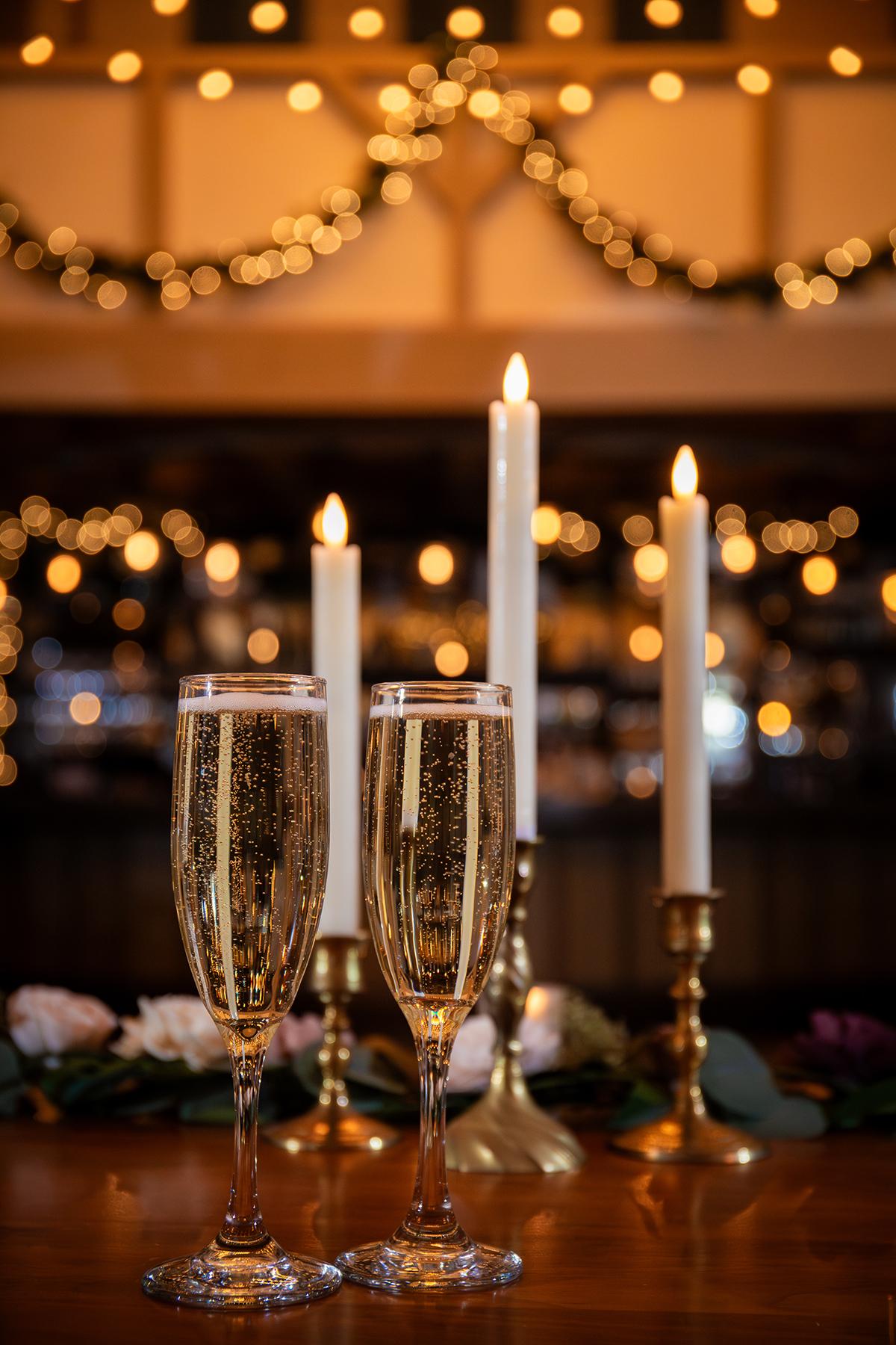 Two champagne glasses and lit candles on a festive table.