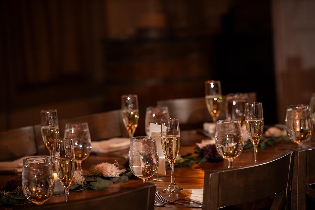 Dimly lit dining table with champagne glasses and floral decorations.