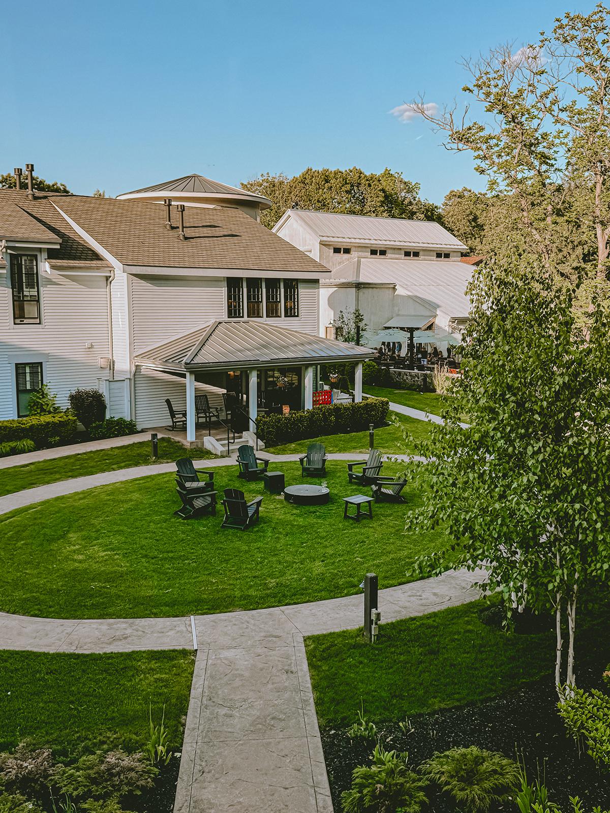 Circular lawn with chairs, surrounded by buildings and trees under a clear blue sky.