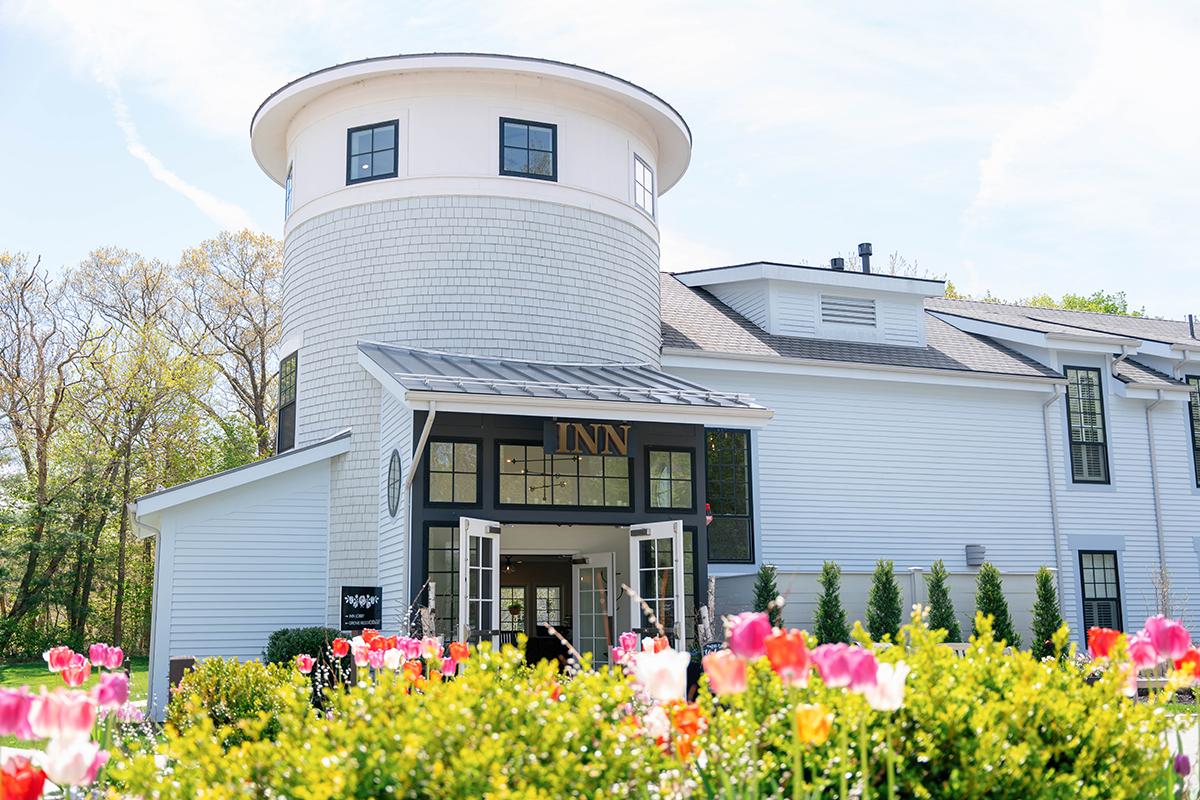 White inn with tower, surrounded by blooming tulips under a blue sky.